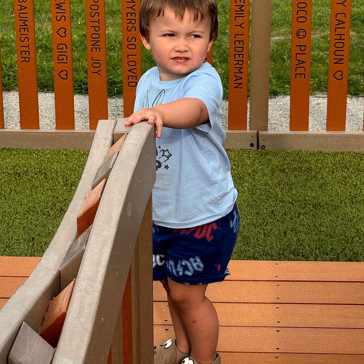 Uhtred joined the competition — help win amazing prizes! background, boy, child, curious, daytime, expression, fence, footwear, grass, messages, names, outdoor, playful, railing, sandals, shirt, shorts, standing, summer, wooden_deck