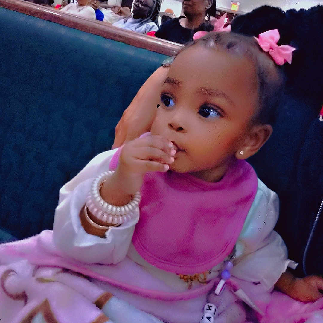Ma'Nari joined the competition — help win amazing prizes! toddler, child, baby, pink_bows, blanket, bib, bracelet, indoor, people, audience, seated, church, banner, curious, portrait, cute, clothing, face, young_child, event