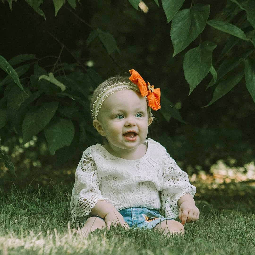 Lynlee is registered to the contest to win money with this photo: adaptation, baby, cheek, child, eye, face, fun, grass, hair_accessory, happy, head, leaf, person, photography, plant, play, portrait, portrait_photography, sitting, smile