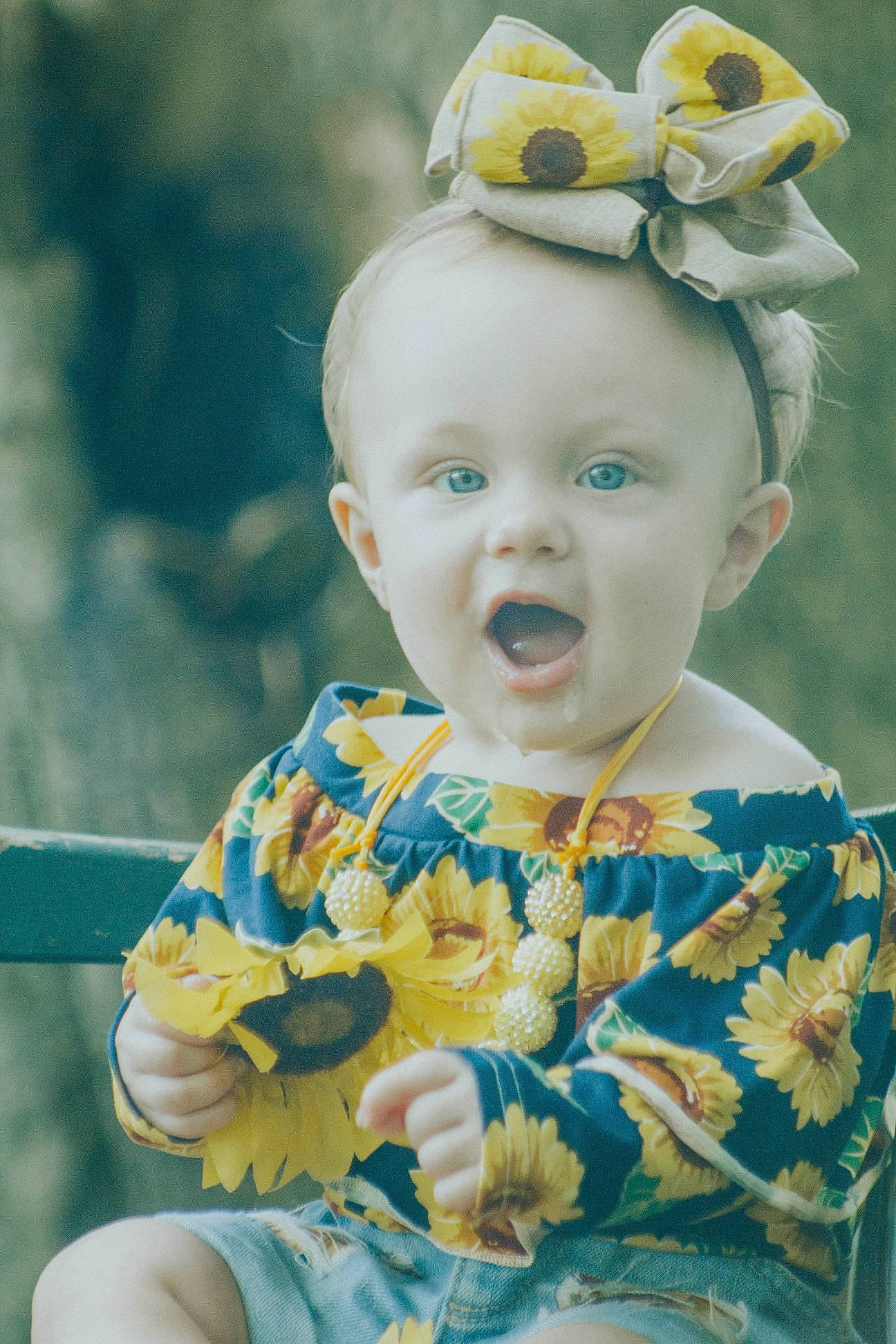 Lynlee joined the competition — help win amazing prizes! baby, cheek, child, ear, eye, face, flower, hair_accessory, head, person, photograph, photography, plant, portrait, smile, spring, surprise, toddler, yellow