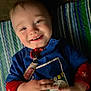 baby, blanket, blue_shirt, child, closeup, clothing, cute, expression, face, hands, happy, indoor, person, portrait, red_sleeves, skin, smiling, striped, toddler, young_child