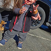 Victoria joined the competition — help win amazing prizes! toddler, child, smile, happy, standing, jacket, fuzzy_jacket, sneakers, blue_shoes, hand, adult_hand, parking_lot, car, tire, wheel, asphalt, outdoor, long_hair, winter_clothing, portrait