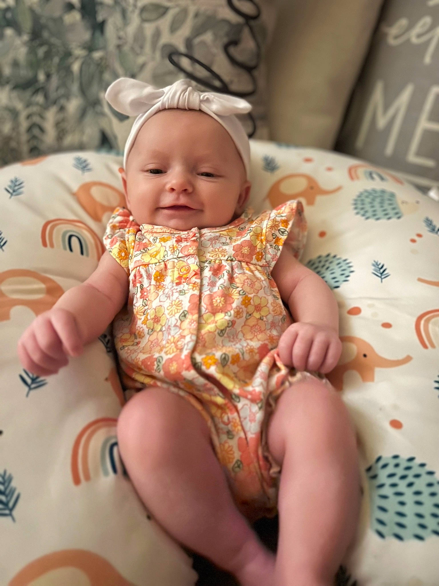 Amaya is registered to the contest to win money with this photo: baby, baby_toddler_clothing, cheek, comfort, dress, eye, finger, foot, happy, head, human_leg, iris, linens, pattern, person, pink, sitting, skin, smile, thigh