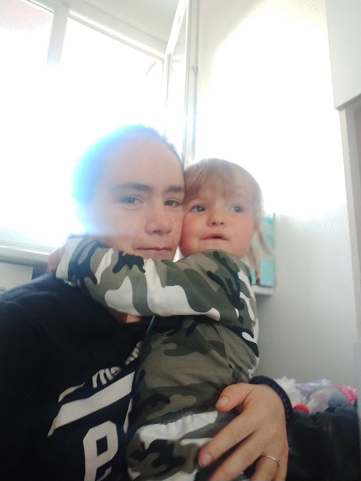 Helena a rejoint le concours — aidez-le/la à gagner de superbes lots ! baby, child, eyebrow, fun, fur, gesture, hairstyle, happy, hug, interaction, military_camouflage, military_uniform, person, personal_protective_equipment, sitting, smile, soldier, t_shirt, thumb, toddler