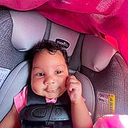 Kyomi joined the competition — help win amazing prizes! baby, child, infant, car_seat, safety_harness, pink_blanket, pink_clothing, smiling, happy, portrait, face, curly_hair, fist, sitting, vehicle_interior, travel, cushion, fabric, close_up, adorable