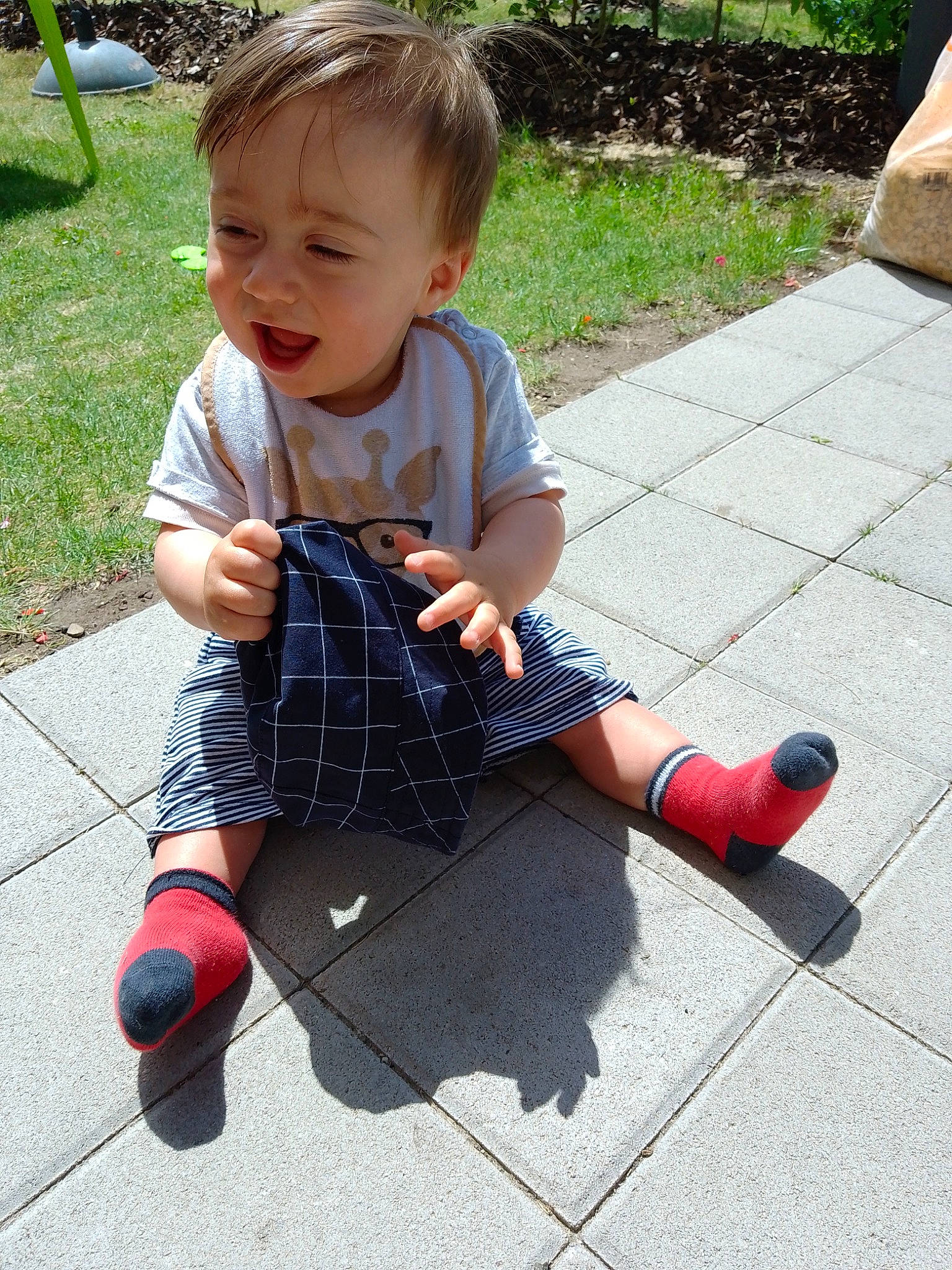 Tiago participe au concours pour gagner de l'argent avec cette photo : asphalt, baby_toddler_clothing, child, dress, face, fun, grass, hairstyle, head, leisure, pattern, person, plaid, plant, road_surface, sidewalk, smile, tartan, toddler, toy