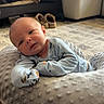 baby, infant, cushion, carpet, sofa, shoes, home_interior, soft_texture, clothing, person, floor, resting, cute, indoor, newborn, head, face, relaxed, child, lying_down