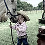 child, horse, cowboy_hat, belt, grass, fence, outdoor, animal, pet, nature, field, ranch, toddler, holding, rope, jeans, striped_shirt, head_touching, calm, daytime