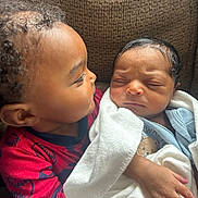 Karter is registered to the contest to win money with this photo: baby, child, newborn, couch, blanket, love, family, indoors, cute, toddler, affection, holding, portrait, warmth, closeup, sibling, curly_hair, red_clothing, soft_light, cozy