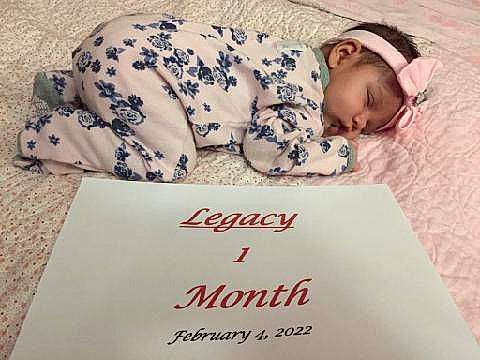 Legacy is registered to the contest to win money with this photo: baby, book, book_cover, carmine, child, cloud, comfort, facial_expression, flooring, font, happy, headwear, illustration, linens, pattern, person, photo_caption, publication, sitting, sleeve