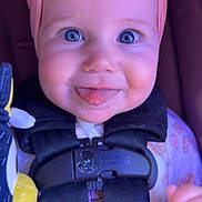 Paisley is registered to the contest to win money with this photo: baby, blue_eyes, car_seat, child, closeup, clothing, cute, face, happy, headband, indoors, infant, person, pink_bow, portrait, safety_harness, seat, smiling, tongue_out, toy