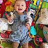 baby, smiling, child, play_mat, toy, colorful, overalls, tights, indoor, happy, cute, infant, lying_down, plush_toy, bright_colors, patterned_clothing, playtime, person, young_child, cheerful