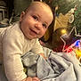 Enzo is registered to the contest to win money with this photo: baby, infant, smiling, blanket, christmas_tree, ornament, star, lights, cozy, sweater, indoor, holiday, decorations, cute, child, portrait, crawling, festive, home, celebration