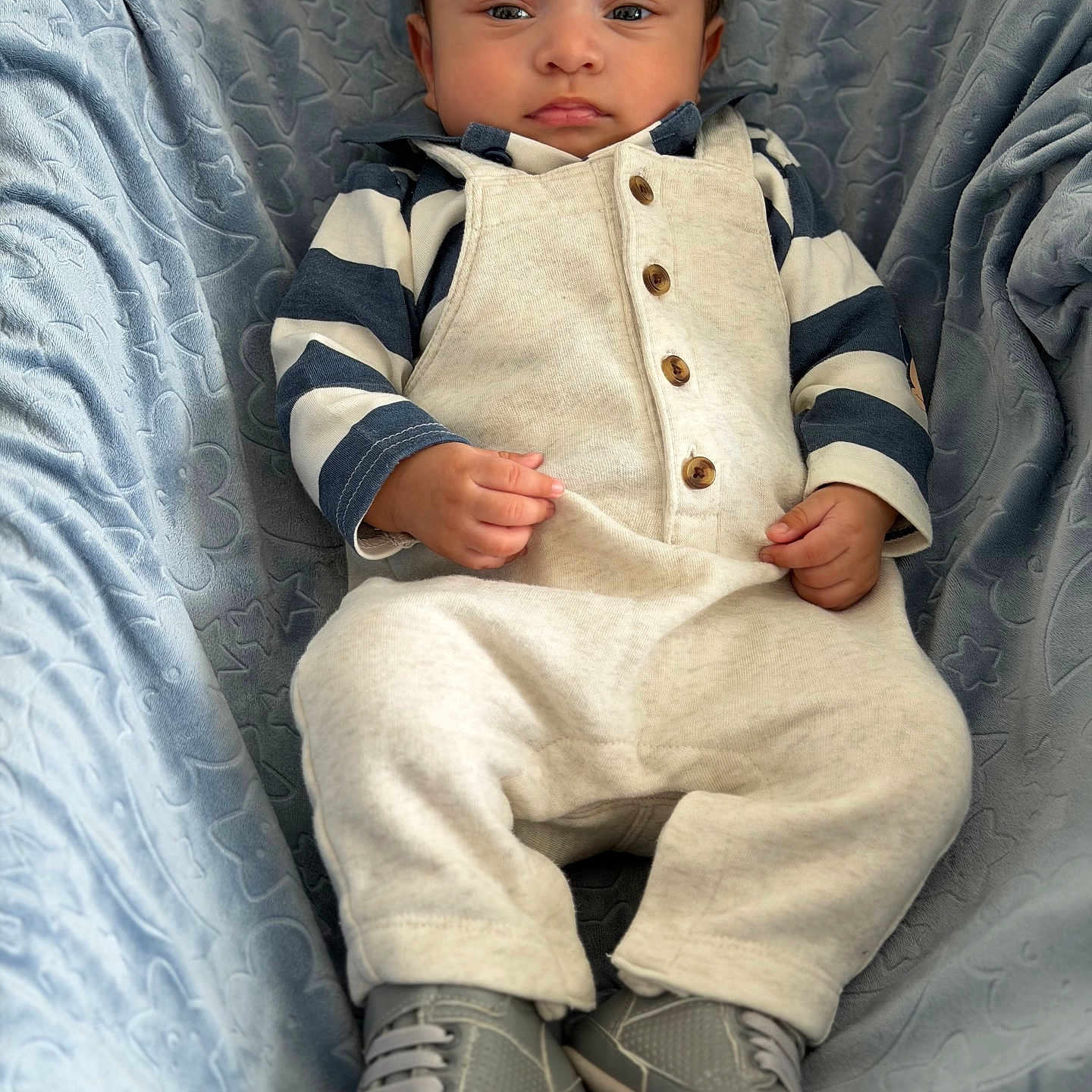 Lucas Moisés joined the competition — help win amazing prizes! baby, infant, child, portrait, sitting, serious, cap, hat, overalls, striped_shirt, sneakers, shoes, blue_chair, upholstery, patterned_fabric, indoor, fashion, closeup, front_facing, cozy