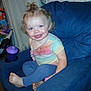 Stormie is registered to the contest to win money with this photo: toddler, child, smile, blue_eyes, rainbow_shirt, leggings, barefoot, armchair, indoor, curtains, sippy_cup, toys, happy, hair, person, seated, candid, home, furniture, playroom