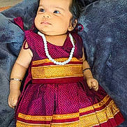 Ruhi is registered to the contest to win money with this photo: baby, infant, traditional_clothing, dress, jewelry, necklace, bracelet, blanket, soft_fabric, indoors, cute, child, portrait, relaxed, skin, foot, hand, floor, curly_hair, lying_down