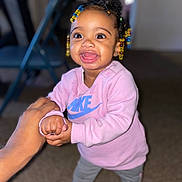Malani is registered to the contest to win money with this photo: adult_hand, carpet, child, clothing, colorful_beads, cute, hair, happy, holding_hands, indoor, joyful, nike, person, portrait, shoes, smiling, standing, sweatshirt, toddler, young_child