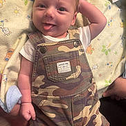 Lux joined the competition — help win amazing prizes! baby, infant, tongue_out, camo_overalls, white_shirt, blanket, cute, smiling, hand, face, lying_down, patterned_blanket, baby_clothes, child, infant_fashion, soft_lighting, indoors, happy, portrait, playful