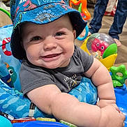 Cashus joined the competition — help win amazing prizes! activity_center, baby, blue, bucket_hat, child, clothing, colorful, cute, face, floor, happy, hat, indoor, infant, legs, person, plush_toy, sitting, smiling, toy