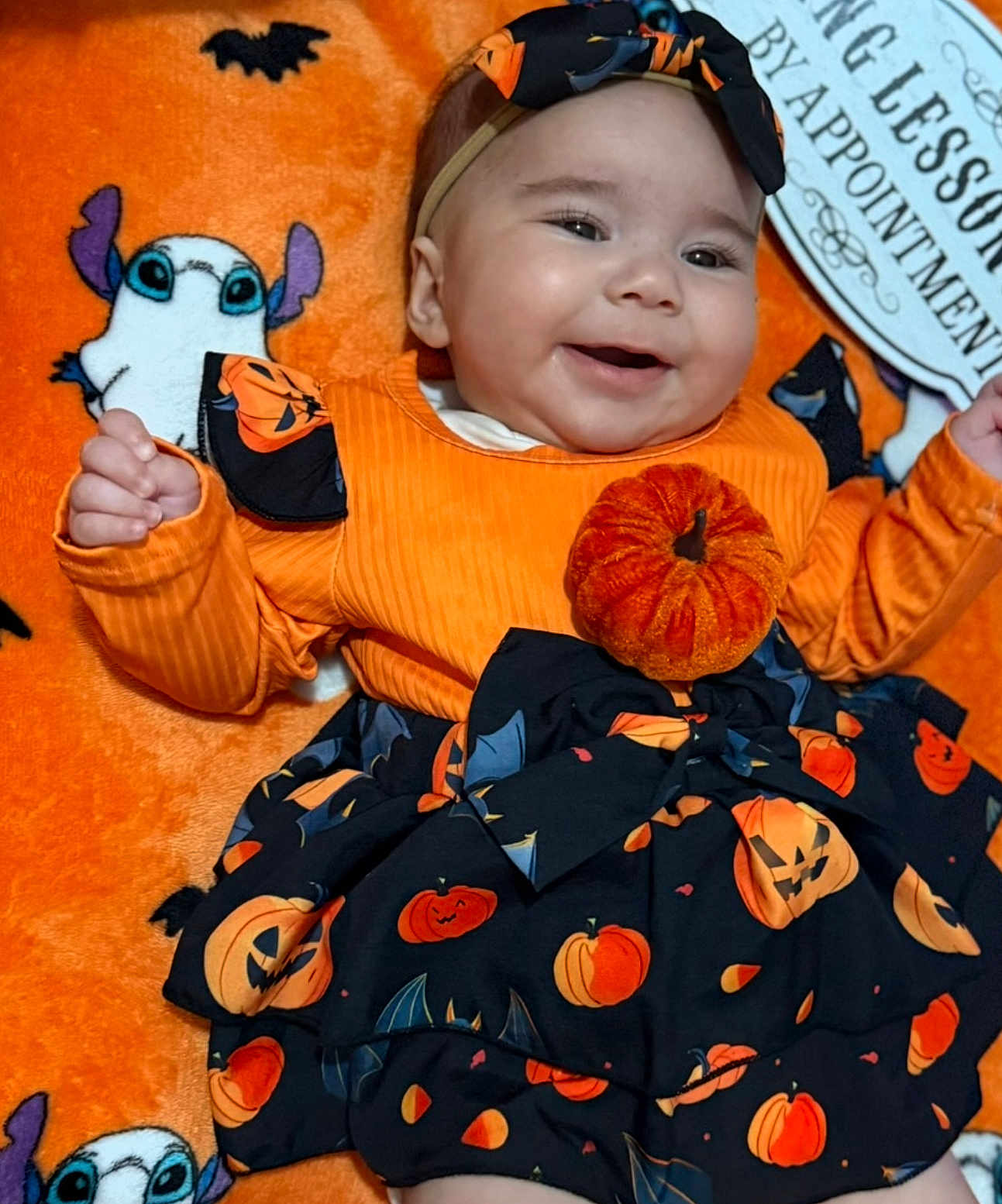 Emine joined the competition — help win amazing prizes! baby, smiling, halloween, pumpkin, bat, orange_clothing, headband, blanket, cartoon_ghost, cute, festive, infant, happy, costume, black_skirt, patterned_clothing, baby_girl, lying_down, indoor, celebration