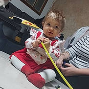 Kaïssy participe au concours pour gagner de l'argent avec cette photo : baby, child, toddler, floor, toy, measuring_tape, dog, couch, window, person, arm, hand, striped_clothing, tattoo, red_socks, white_tights, indoor, tile_floor, curly_hair, playful