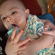 Bryson is registered to the contest to win money with this photo: baby, bottle, hand, face, person, infant, clothing, sleepy, holding, closeup, skin, child, cute, patterned_clothing, feeding, indoors, soft_light, comfort, young, portrait