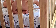 Bryson is registered to the contest to win money with this photo: baby, crib, wooden_bars, smile, infant, nursery, bedding, toy, child, crawling, floor, carpet, indoor, cute, person, happy, face, arms, playful, home