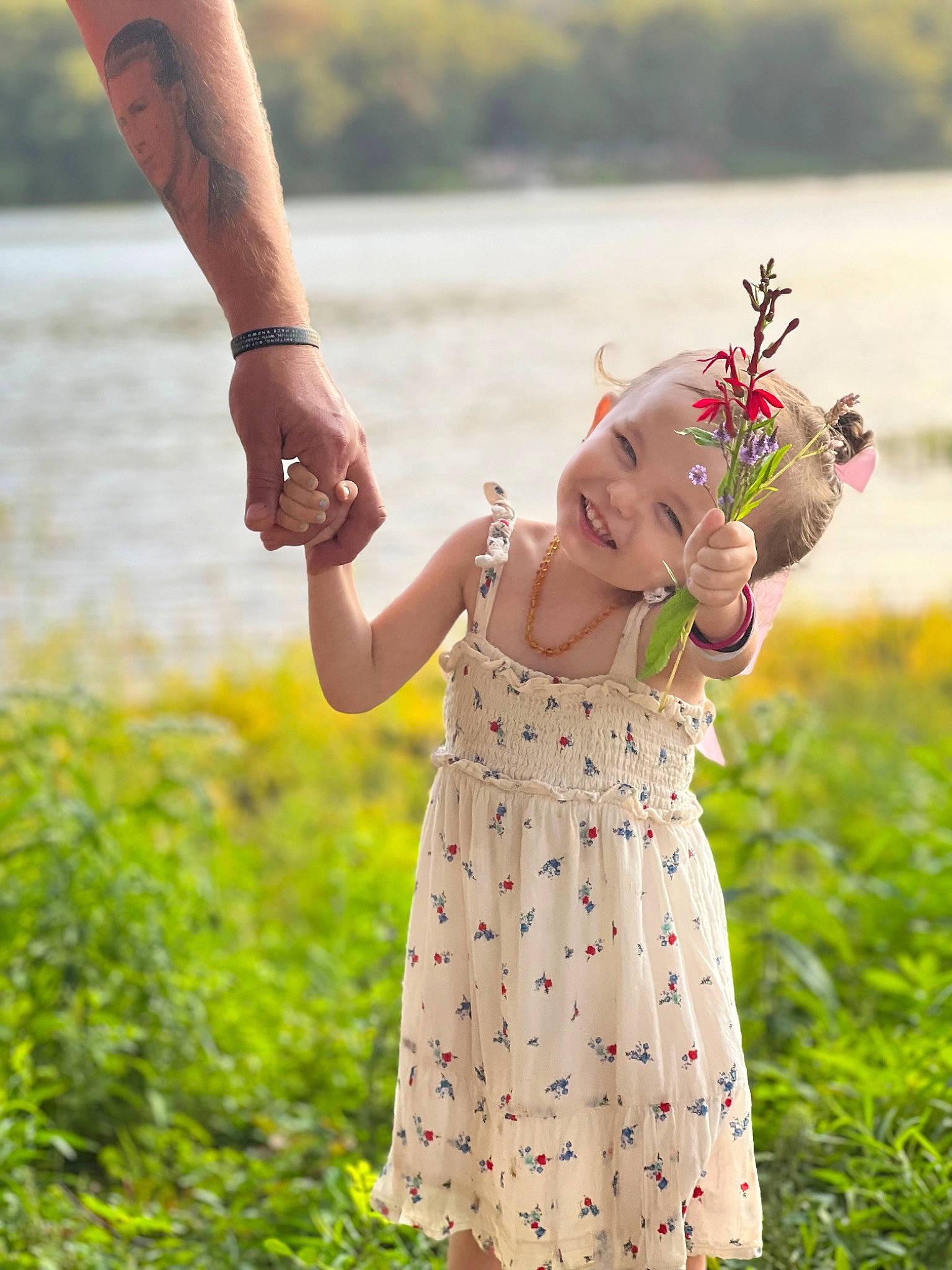 Evangelina is registered to the contest to win money with this photo: arm, baby_toddler_clothing, dress, fawn, finger, flower, gesture, grass, hand, happy, headwear, joy, one_piece_garment, people_in_nature, person, photograph, plant, skin, sleeve, smile