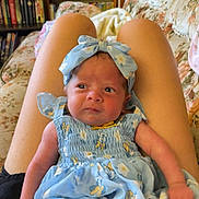 Ahvi joined the competition — help win amazing prizes! baby, child, blue_dress, headband, floral_pattern, sitting, lap, person, indoor, living_room, couch, bookshelf, furniture, curious_expression, skin, clothing, portrait, infant, cute, cozy