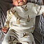 baby, child, smile, pajamas, bunny_pattern, blanket, lying_down, cozy, cute, infant, soft_texture, happy, indoors, comfortable, socks, small_hands, head, face, relaxed, toddler