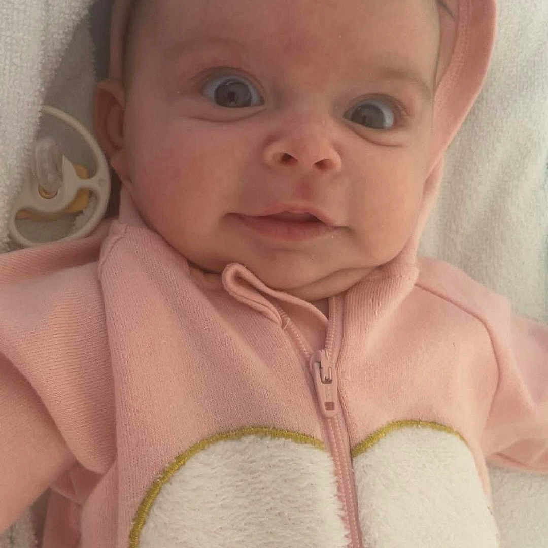 Andrea participe au concours pour gagner de l'argent avec cette photo : adorable, baby, baby_girl, blanket, child, clothing, cute, expression, face, heart, hood, infant, lying_down, pacifier, pink_hoodie, portrait, soft_texture, wide_eyes, young, zipped_jacket