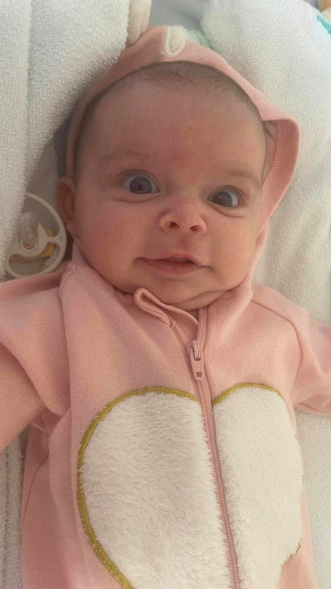 Andrea participe au concours pour gagner de l'argent avec cette photo : baby, infant, pink_hoodie, heart, pacifier, blanket, face, wide_eyes, cute, child, soft_texture, clothing, portrait, lying_down, young, adorable, baby_girl, expression, hood, zipped_jacket