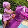 Lyna participe au concours pour gagner de l'argent avec cette photo : child, toddler, pink_clothing, headscarf, playground_ride, purple_dragon, outdoor, daylight, greenery, toy, play, focused, childhood, sneakers, casual_wear, handlebars, amusement, park, cute, adventure
