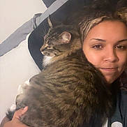 Smokey is registered to the contest to win money with this photo: person, cat, tabby_cat, pet, bed, pillow, blanket, hug, cozy, indoor, close_up, striped_fur, long_hair, nose_piercing, hand, t_shirt, portrait, resting, whiskers, couch