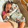 baby, sleeping, blanket, pacifier, baby_rocker, cushion, polka_dot, pink_clothing, hair_bow, infant, cozy, indoor, cute, child, soft_fabric, resting, toddler, peaceful, nursery, relaxing