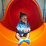 child, toddler, pacifier, denim_jacket, orange_slide, playground, shoes, indoor, curious, sitting, baby, shorts, toy, play, fun, young, cute, leisure, person, slide