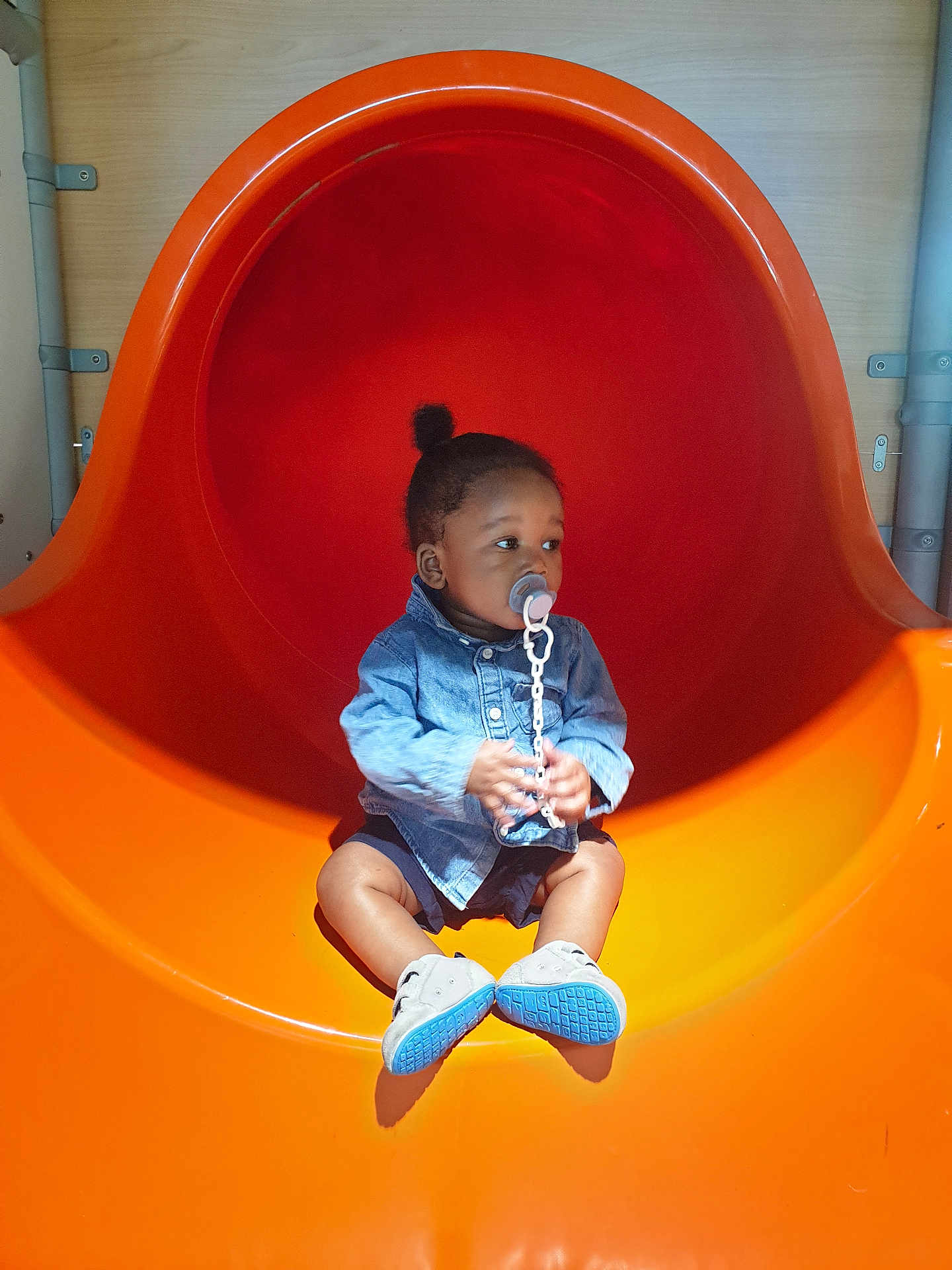 Ablet Prince Laël a rejoint le concours — aidez-le/la à gagner de superbes lots ! child, toddler, pacifier, denim_jacket, orange_slide, playground, shoes, indoor, curious, sitting, baby, shorts, toy, play, fun, young, cute, leisure, person, slide