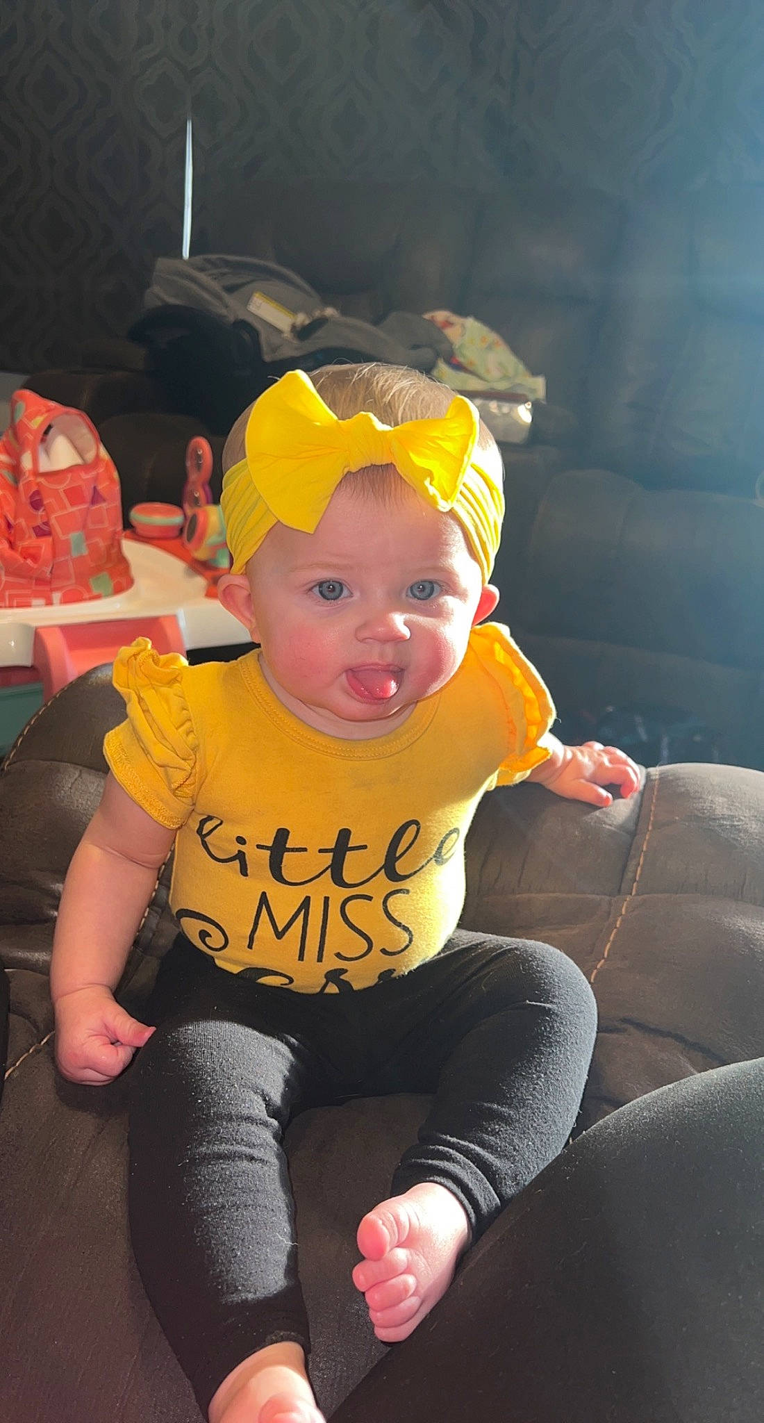 Paisley is registered to the contest to win money with this photo: baby, baby_toddler_clothing, cap, chair, child, eyewear, fun, goggles, happy, hat, headwear, human_leg, lap, leisure, person, personal_protective_equipment, pink, sitting, sunglasses, t_shirt