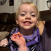 Paisleigh is registered to the contest to win money with this photo: blanket, blonde_hair, child, clock, couch, face, glasses_partial, hand, happy, indoor, living_room, messy_hair, person, pillow, portrait, purple_clothing, smiling, teeth, toddler, zebra_print