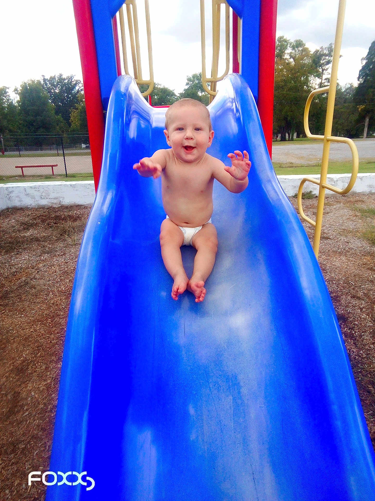 Jordan joined the competition — help win amazing prizes! baby, child, slide, playground, diaper, outdoor, happy, smiling, blue_slide, play_equipment, trees, grass, daylight, fun, park, infant, climbing_frame, bare_chest, recreation, joy