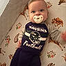 baby, child, infant, pacifier, smiling, wide_eyed, portrait, lying_down, football, sportswear, baltimore_ravens, jersey, helmet, mattress, crib, bedding, woodland_animals, hedgehog, squirrel, floral_pattern