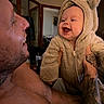 baby, infant, child, adult, father, smiling, laughing, portrait, indoor, home, bear_costume, hood, fuzzy_clothing, tattoo, beard, face, family, holding, interaction, photograph