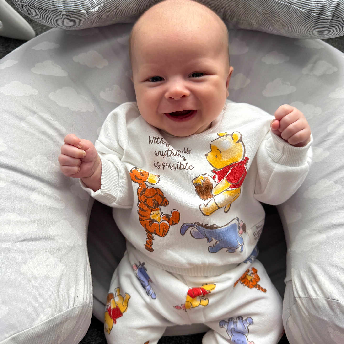 Noah joined the competition — help win amazing prizes! baby, smiling, infant, white_clothing, winnie_the_pooh, tiger, eeyore, cloud_pattern, cushion, soft, happy, cute, indoors, infant_fashion, child, person, portrait, sitting, cozy, playful