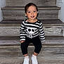 Liliana joined the competition — help win amazing prizes! toddler, child, smiling, stairs, wooden_stairs, striped_shirt, skull_graphic, black_pants, white_sneakers, flowers, indoor, portrait, cute, happy, sitting, young_child, person, casual_clothing, hair, feet