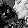 dog, woman, portrait, black_and_white, close_up, face, eyes_closed, curly_hair, fur, affection, nose_to_nose, intimate, love, pet, animal, human, monochrome, profile, hoodie, soft_lighting