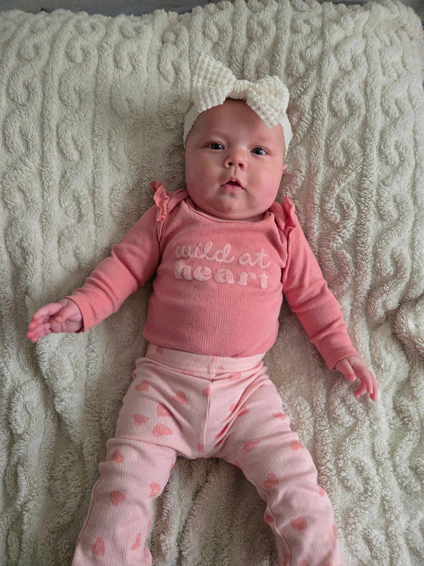 Eren joined the competition — help win amazing prizes! apparel, baby, blanket, bow, child, cozy, cute, expression, face, headband, indoors, infant, long_sleeve, lying_down, patterned_pants, person, pink_clothing, portrait, soft_texture, young_child