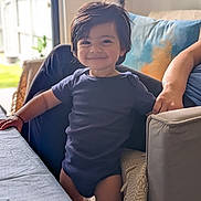 Shawnak joined the competition — help win amazing prizes! toddler, child, smiling, indoor, living_room, couch, pillow, lamp, table, natural_light, happy, person, short_sleeves, dark_hair, standing, home, cozy, casual_clothing, portrait, furniture