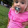 toddler, child, pacifier, pink_clothing, outdoor, grass, trees, playful, cute, young_child, casual_clothing, daylight, nature, portrait, standing, hand_on_hip, star_pattern, curly_hair, closeup, backyard