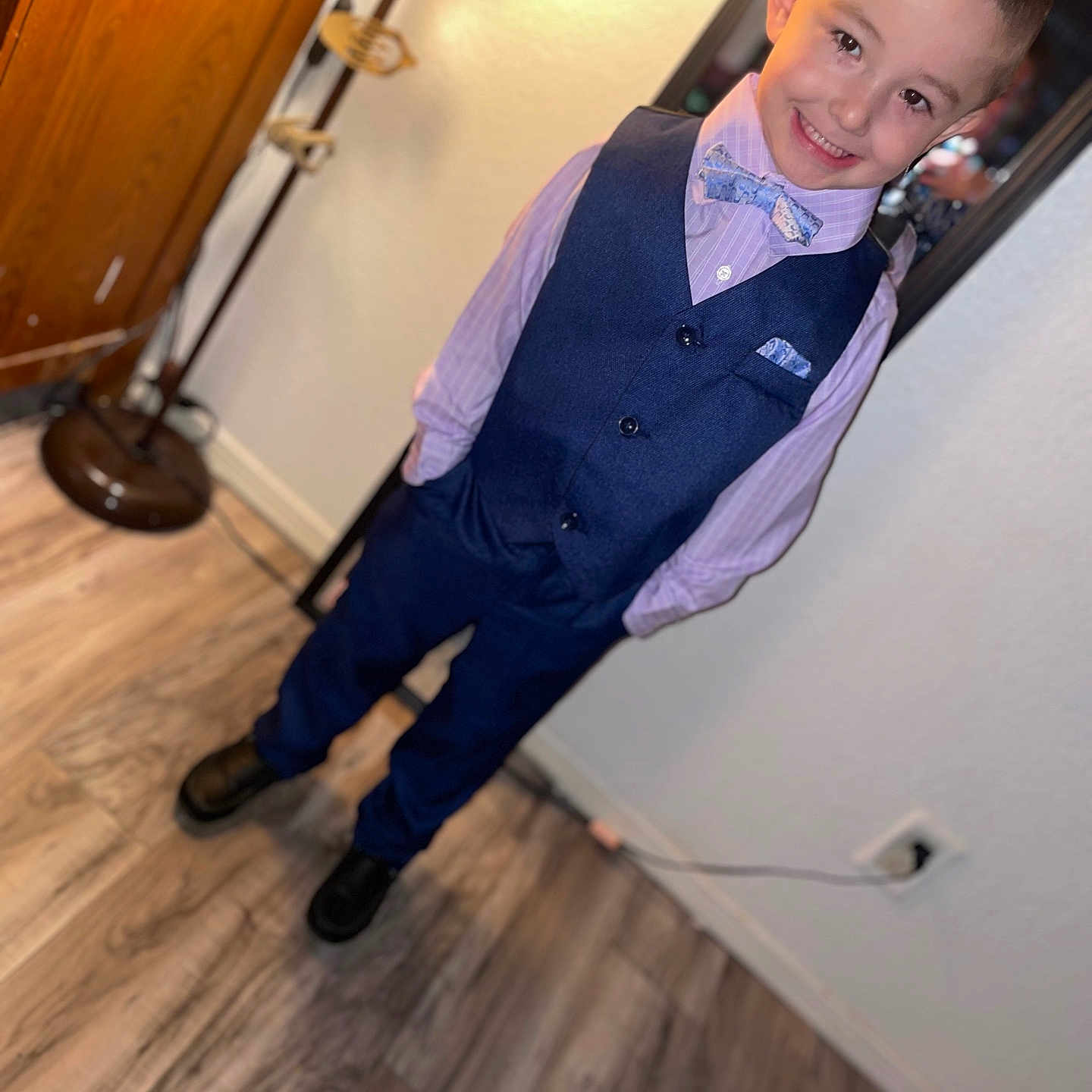 Kane is registered to the contest to win money with this photo: bow_tie, boy, child, coat_rack, dress_shirt, fashion, floor, formal_wear, hairstyle, happy, indoor, lighting, mirror, pants, portrait, posing, shoes, smile, vest, wood_floor