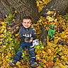 autumn_leaves, casual_clothing, child, fall, green_plants, happy, jeans, nature, outdoor, playful, plush_toy, portrait, seasonal, smiling, sneakers, sunlight, toy, tree, wood, yellow_leaves